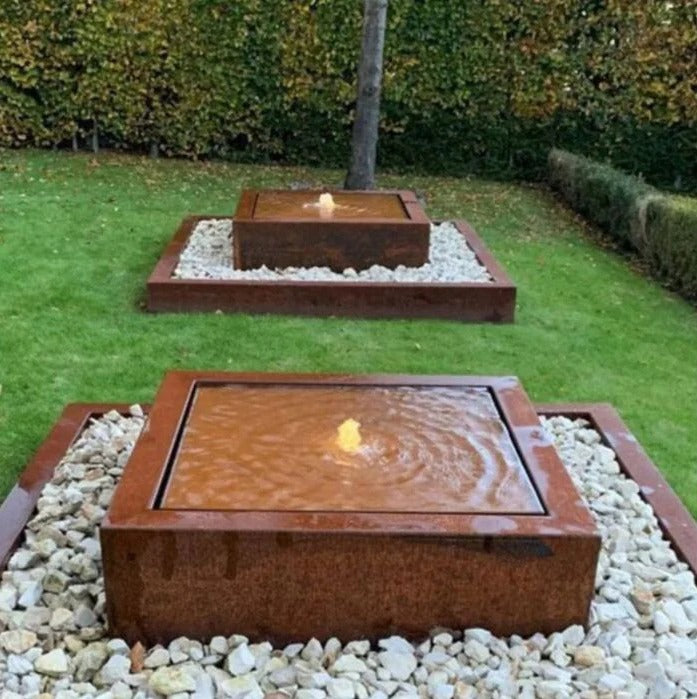 Two Urban Square Fountains with rust patina in a landscaped garden setting, creating a serene water feature.
