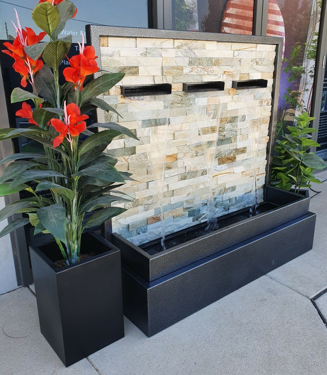 Selene white stacked stone wall water feature with 3 spouts flowing with water into the base.